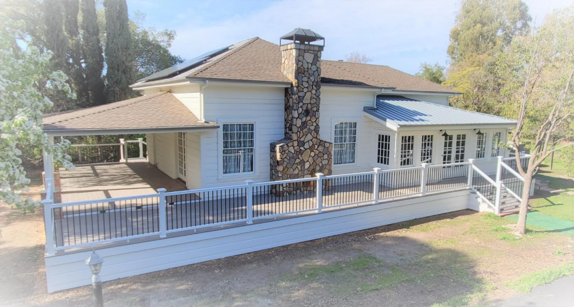 White painted house with a deck wrapping around its entirety.