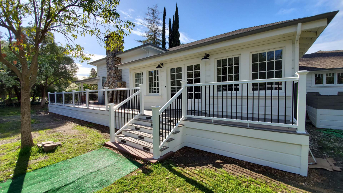 White painted house with a deck wrapping around its entirety.